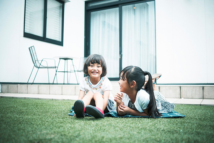 庭の芝生に腰を下ろす女の子二人